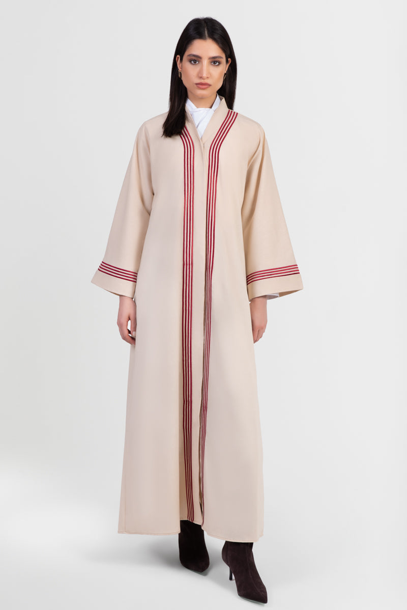 Beige linen abaya with red stripes running vertically around front placket and sleeve cuffs front view