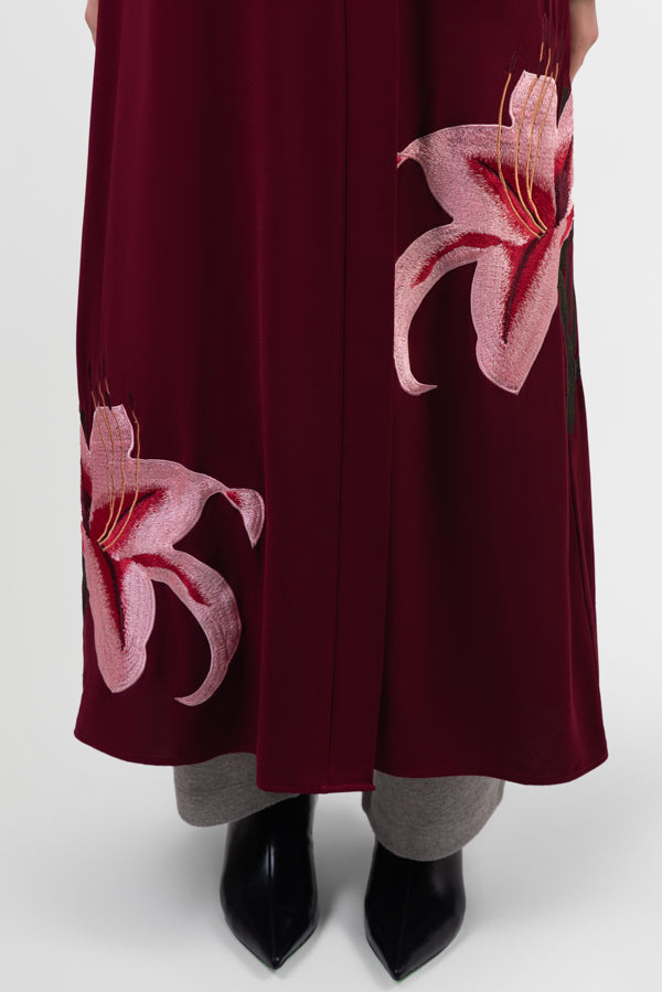 Burgundy abaya with pink lily embroidery around bottom hemline details