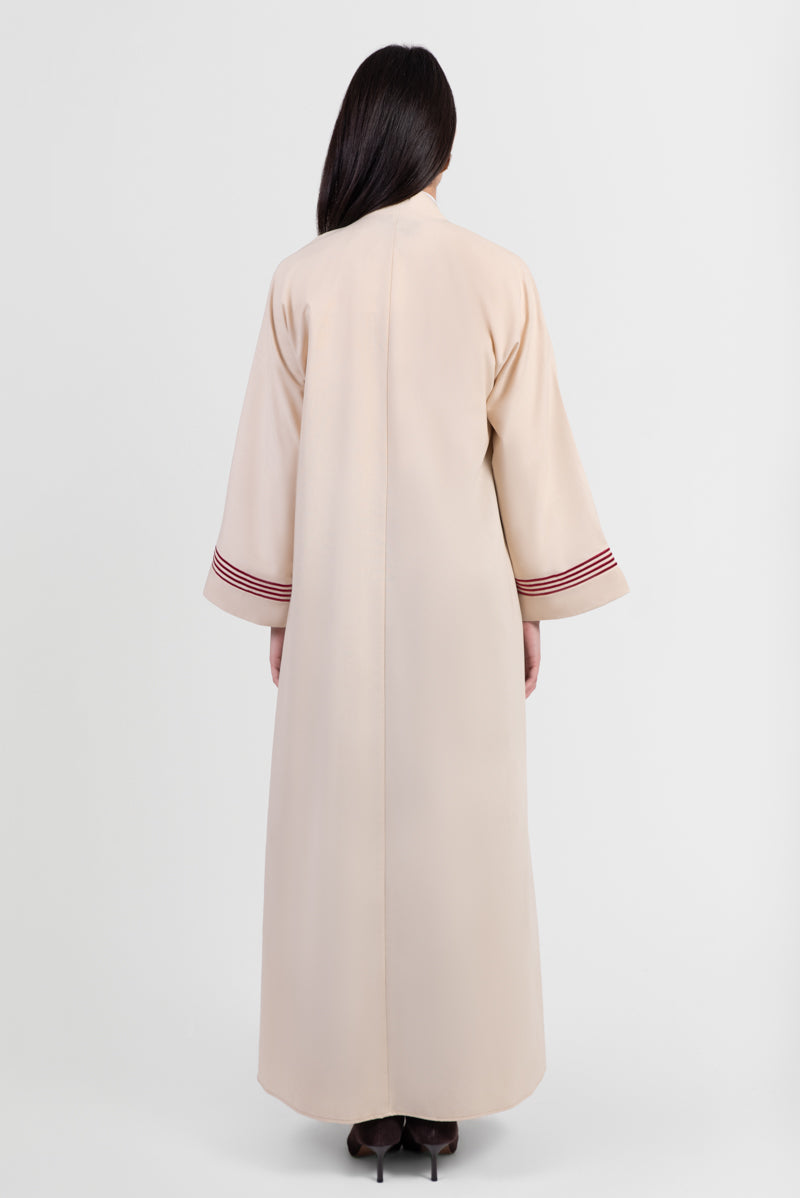Beige linen abaya with red stripes running vertically around front placket and sleeve cuffs back view