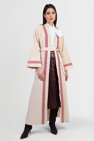 Beige linen abaya with red stripes running vertically around front placket and sleeve cuffs with matching belt front view
