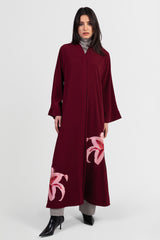 Burgundy abaya with pink lily embroidery around bottom hemline front view