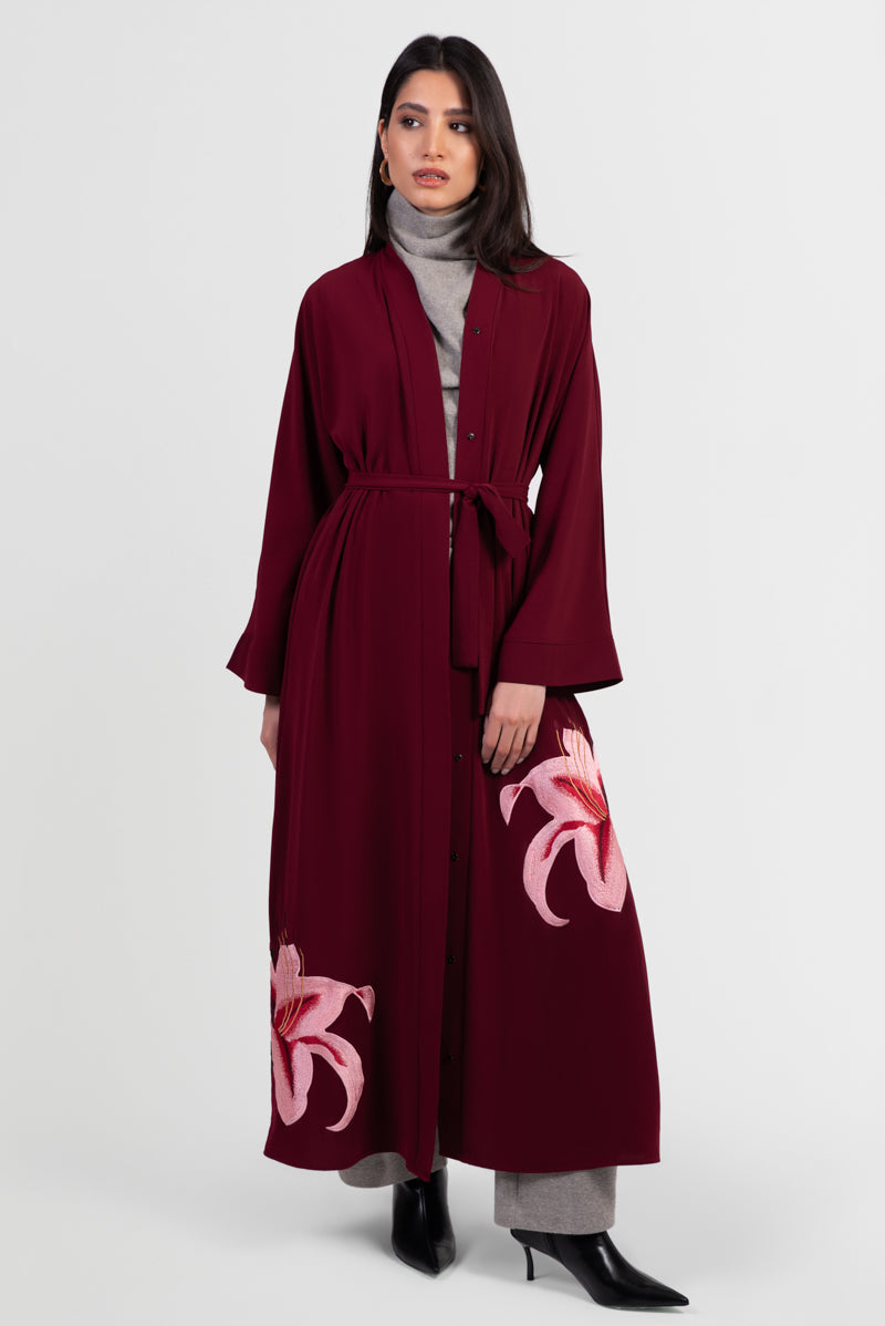 Burgundy abaya with pink lily embroidery around bottom hemline and matching belt