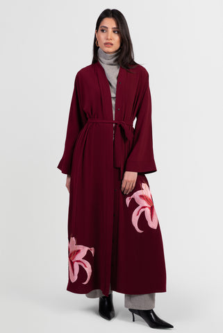 Burgundy abaya with pink lily embroidery around bottom hemline and matching belt
